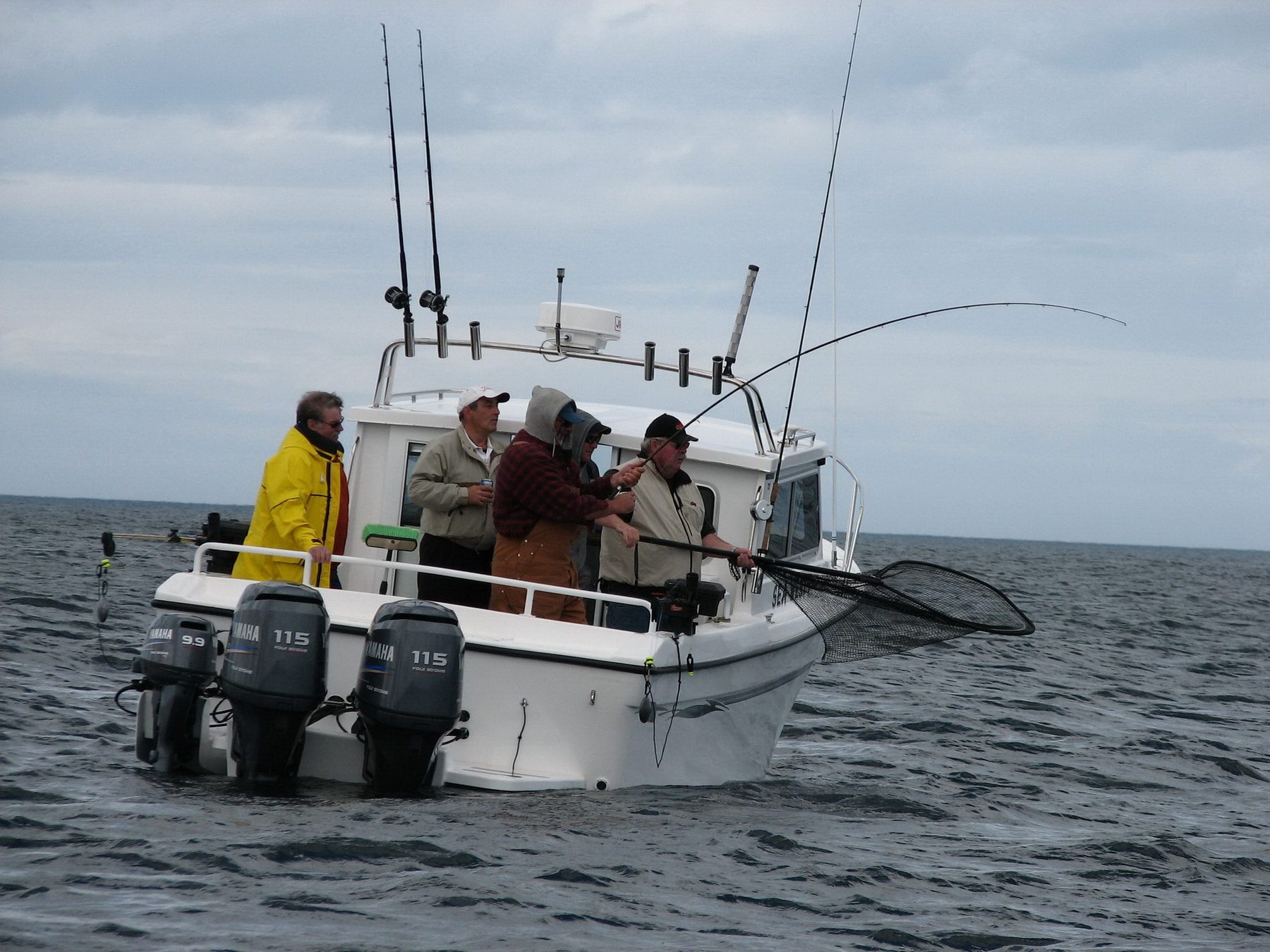 A guide reaching out with a net to land a salmon at the side of the boat